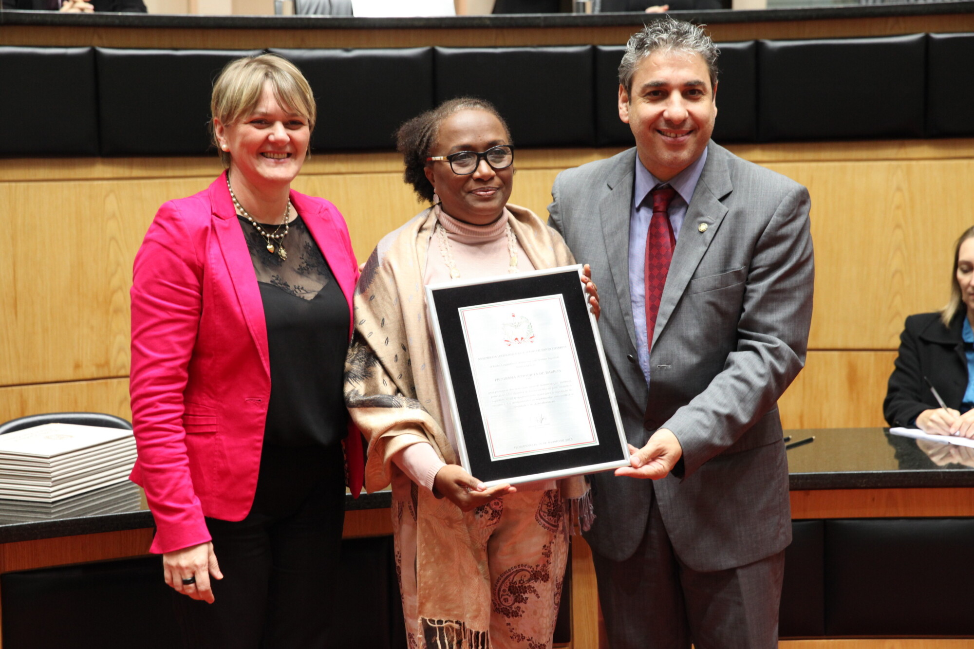 A coordenadora do PAB recebe a homenagem das mãos dos parlamentares