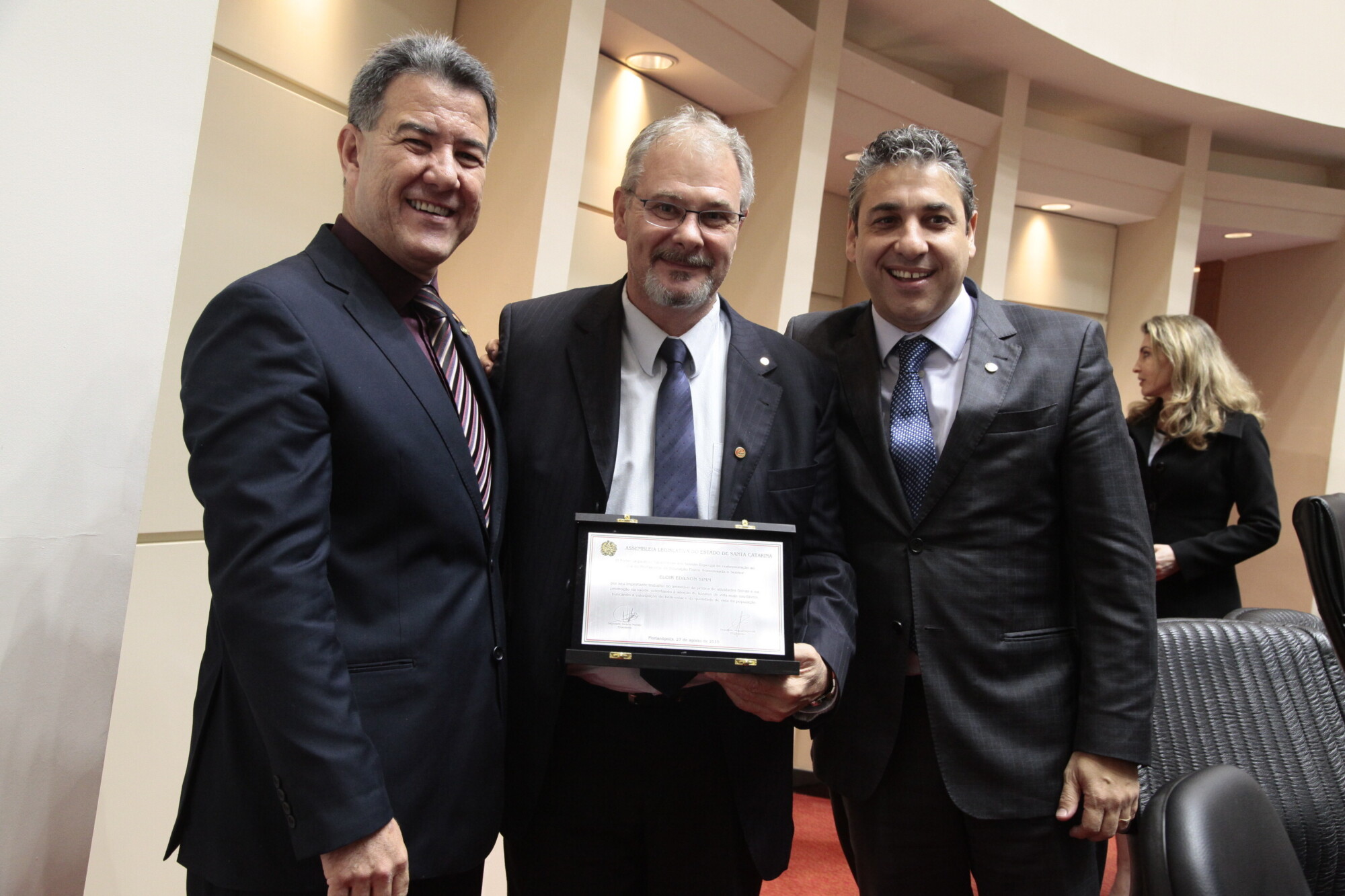 Eloir Edison Simm, presidente do Conselho Estadual de Educação Física, recebe placa comemorativa dos deputados Jean e Mario Marcondes