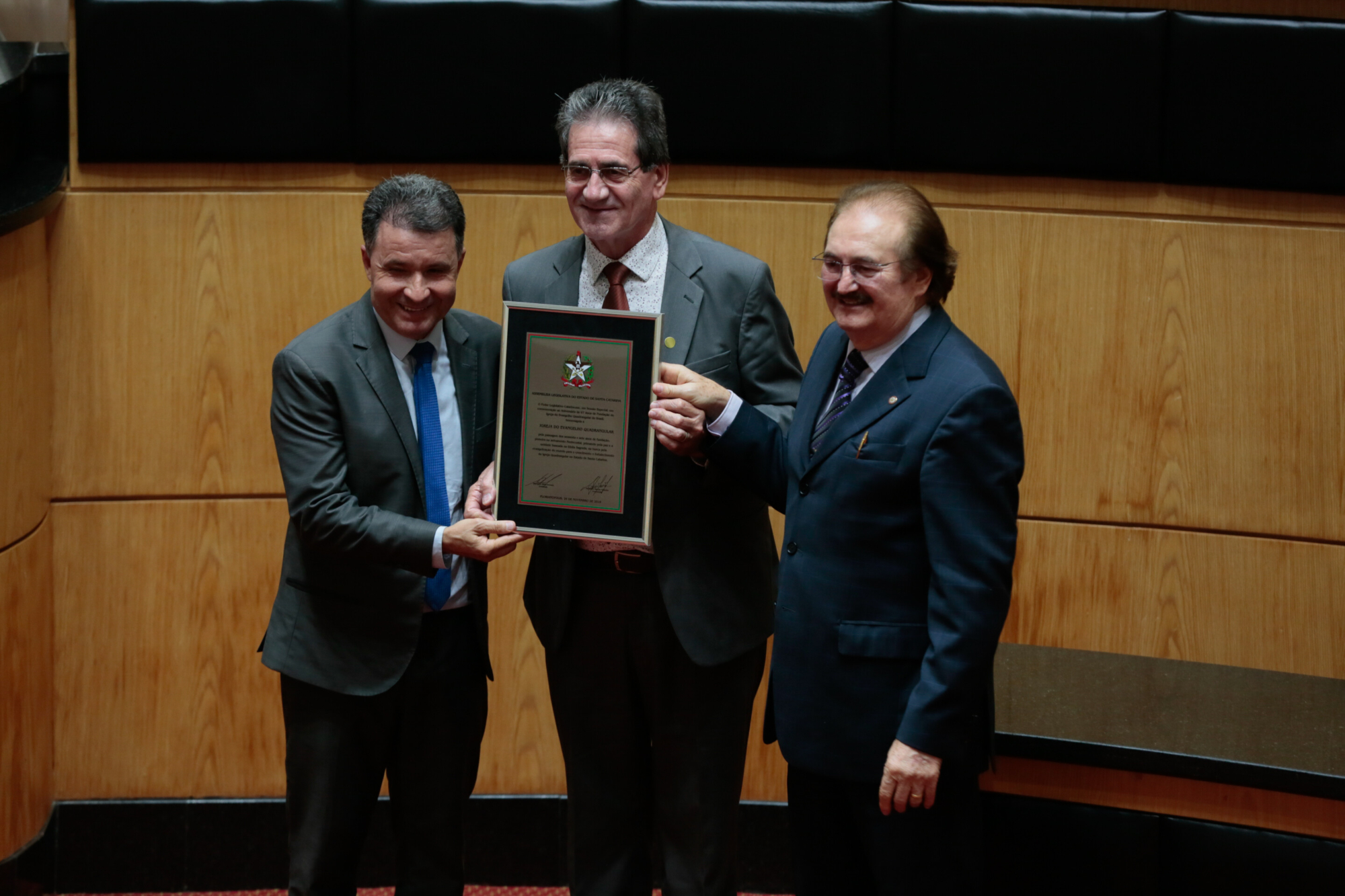 Cecílio de Farias Neto (centro) recebe homenagem para a IEQ das mãos de Darci de Matos (e) e Narcizo Parisotto