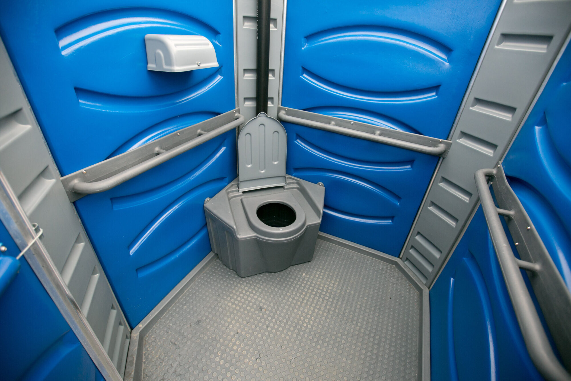 Vista interna de banheiro químico acessível a pessoas com deficiência ou com mobilidade reduzida.