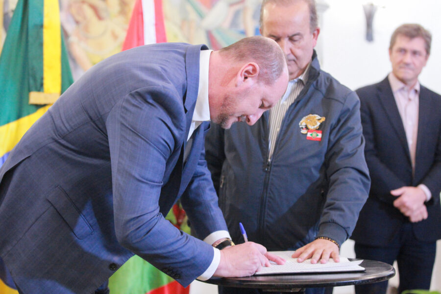 Observado por Jorginho Mello, De Nadal assina o termo de posse no cargo de governador do Estado