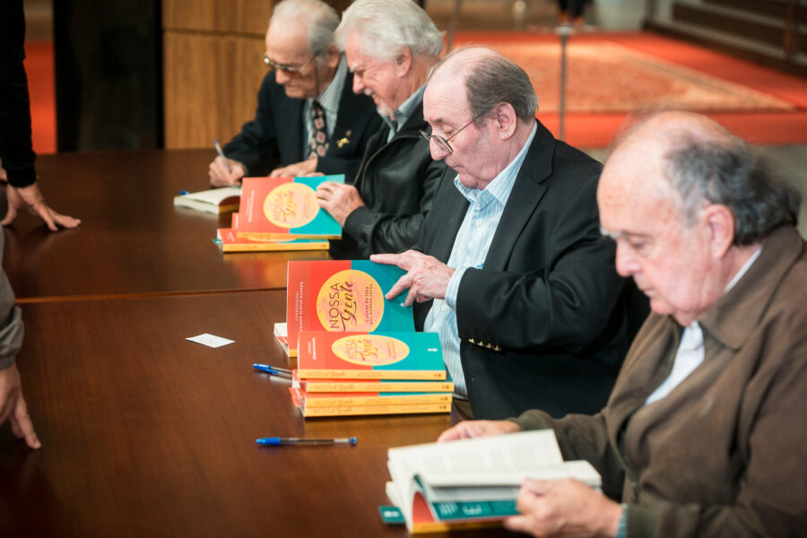 Autores assinando o livro.