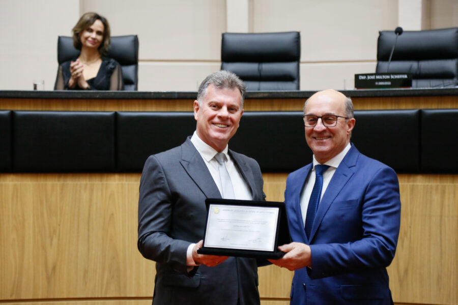 Giovani Nascimento, presidente da Fehoesc, recebe placa comemorativa das mãos do deputado José Milton Scheffer.
