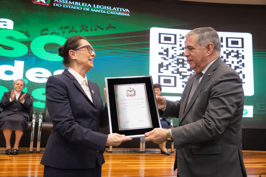 Deputado Mário Motta entrega placa comemorativa à diretora-geral do Centro Educacional Menino Jesus, irmã Marli Schlindwein.